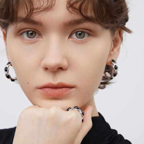 Close-up of TIKOO black onyx earrings, showcasing the high-shine platinum finish and hand-set stones.
