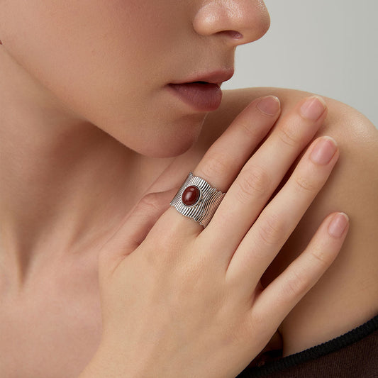 Close-up of a model wearing the TIKOO bold red stone wide band ring in platinum finish.