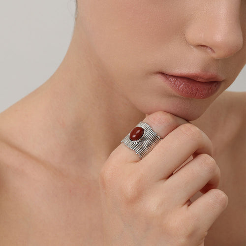 Close-up of a model wearing the TIKOO bold red stone wide band ring in platinum finish.