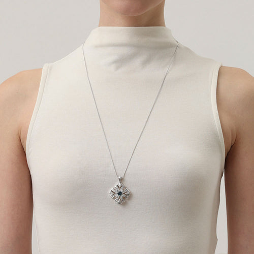 Model wearing TIKOO London blue topaz long necklace with a white high-neck sleeveless top.