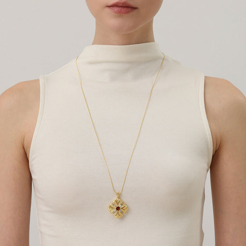 A model wearing the TIKOO long garnet necklace to show the elegant drop and scale of the vintage floral pendant.