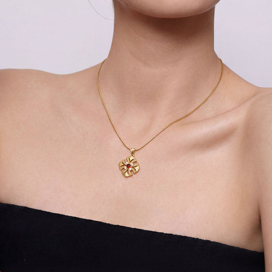 Close-up of a model wearing TIKOO Art Deco floral necklace with a deep red garnet gemstone.