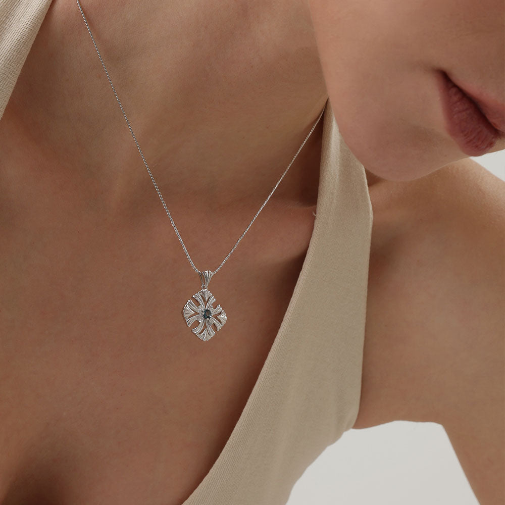 Side view of a model styling the TIKOO topaz necklace, demonstrating its elegant drop and shimmer.