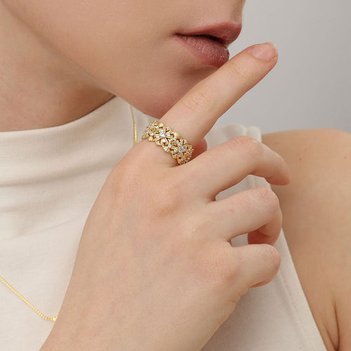 Close-up of model wearing a vintage-style gold floral Moissanite ring on finger.