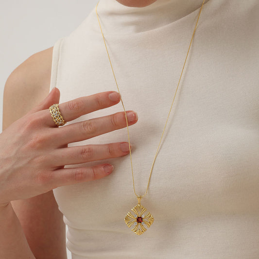 Model showcasing TIKOO floral gold ring paired with a matching garnet cross pendant necklace.