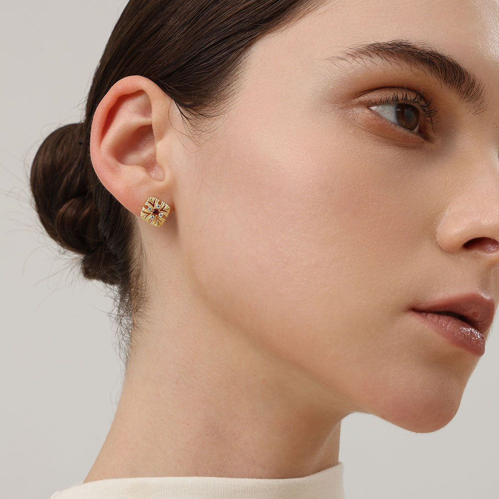 Side profile of a model showcasing the intricate vintage cross flower design of the TIKOO garnet earrings.