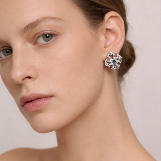 Close-up of a model wearing TIKOO Art Deco floral earrings with blue gemstone and sparkling accents.
