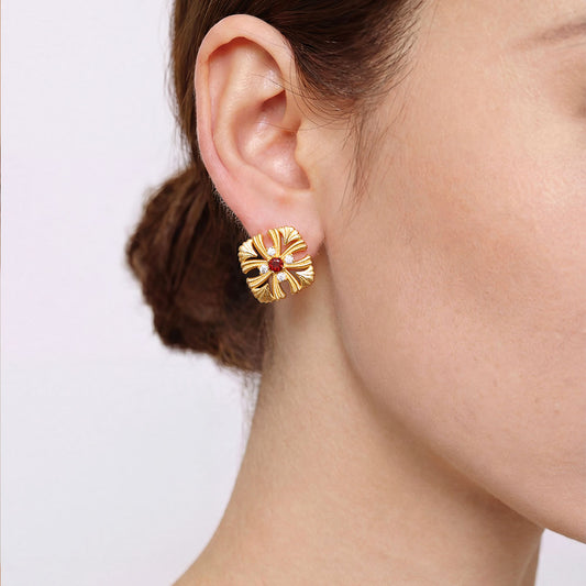 Close-up shot of a model wearing TIKOO 18k gold vintage-inspired floral earrings with natural garnet centerpiece