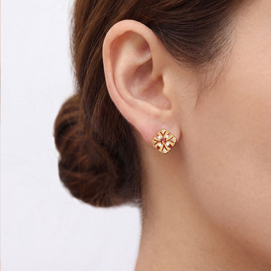 Close-up shot of a model wearing TIKOO 18k gold vintage-inspired floral earrings with natural garnet centerpiece