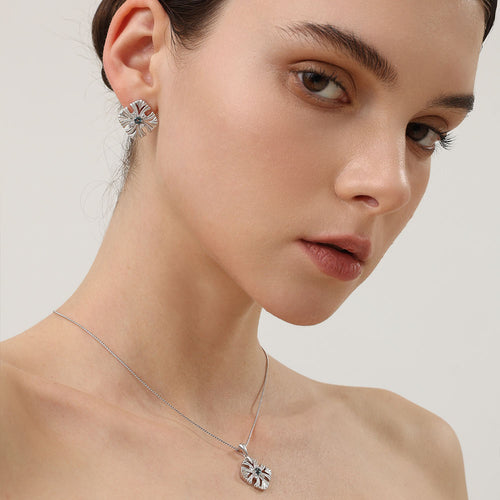 Model styling the TIKOO topaz earrings with a matching blue stone cross pendant for a complete luxury look.
