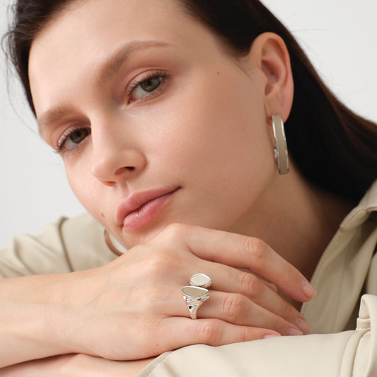 Close-up of a model wearing the TIKOO leather inlay statement ring, showcasing the organic pebble design and neutral tones.