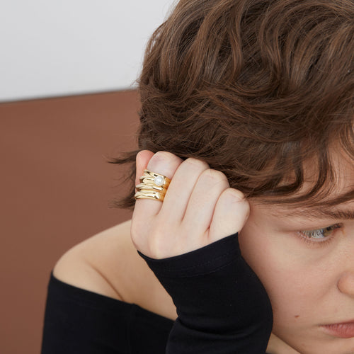 Model wearing a TIKOO bold wavy gold statement ring with pearl, showcasing a luxury fashion look.