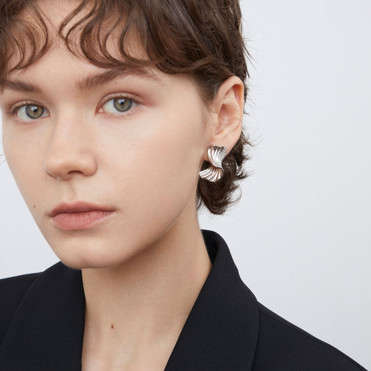 Close-up of TIKOO heavy white gold plated ribbed texture earrings on a model, highlighting the fluid metal design.