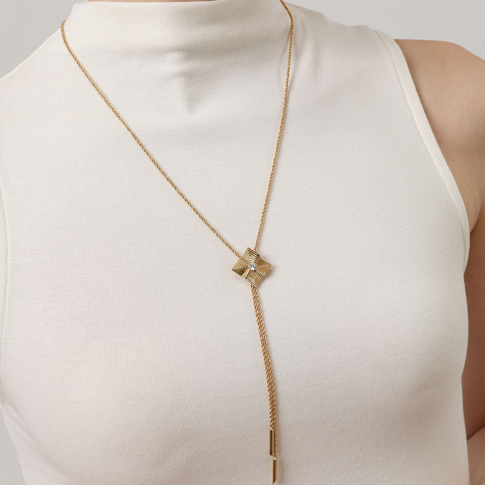 Model wearing TIKOO long geometric necklace over a white mock neck top, showcasing the elongated chain style.