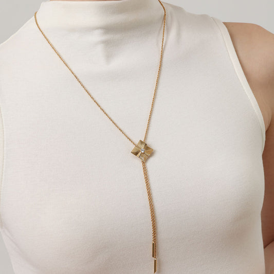 Model wearing TIKOO long geometric necklace over a white mock neck top, showcasing the elongated chain style.