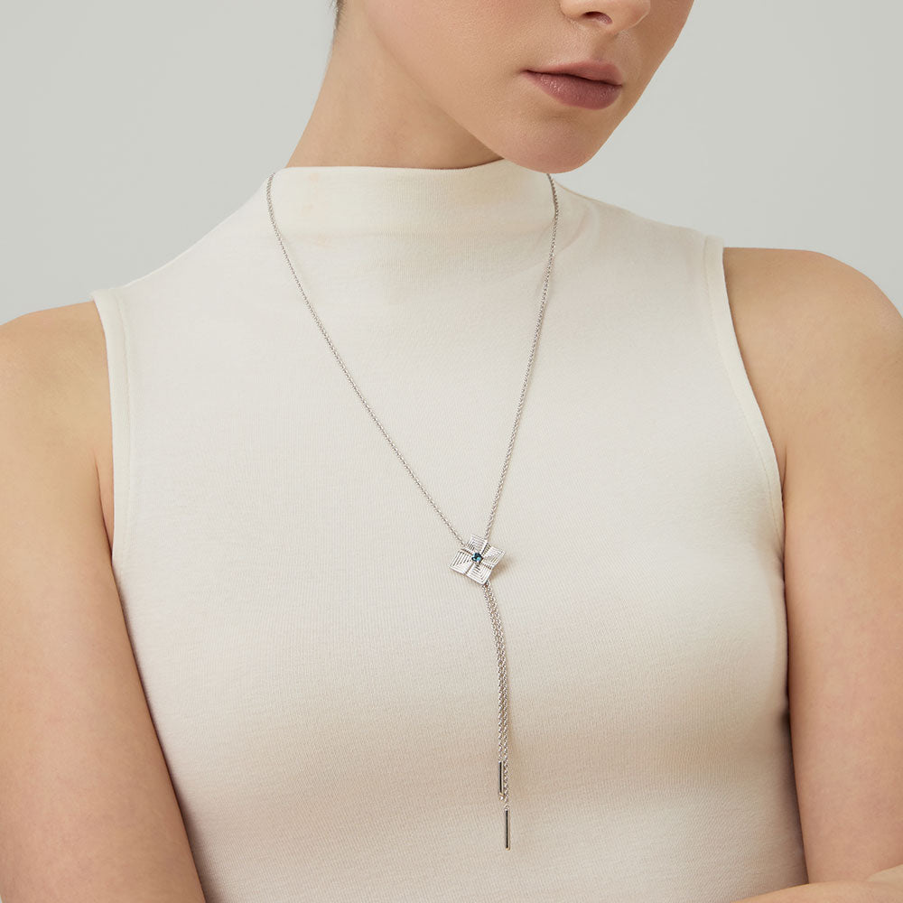 Model wearing TIKOO original London blue topaz long necklace over a high-neck white top, showcasing the elegant drop.