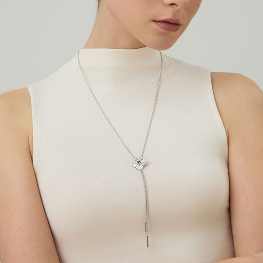 Model wearing TIKOO original London blue topaz long necklace over a high-neck white top, showcasing the elegant drop.
